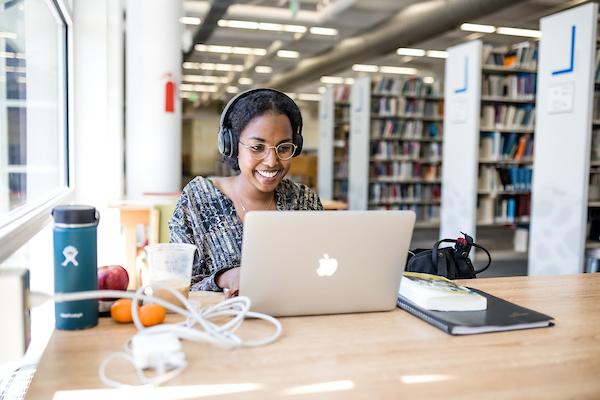 Smiling student working at her laptop in the library