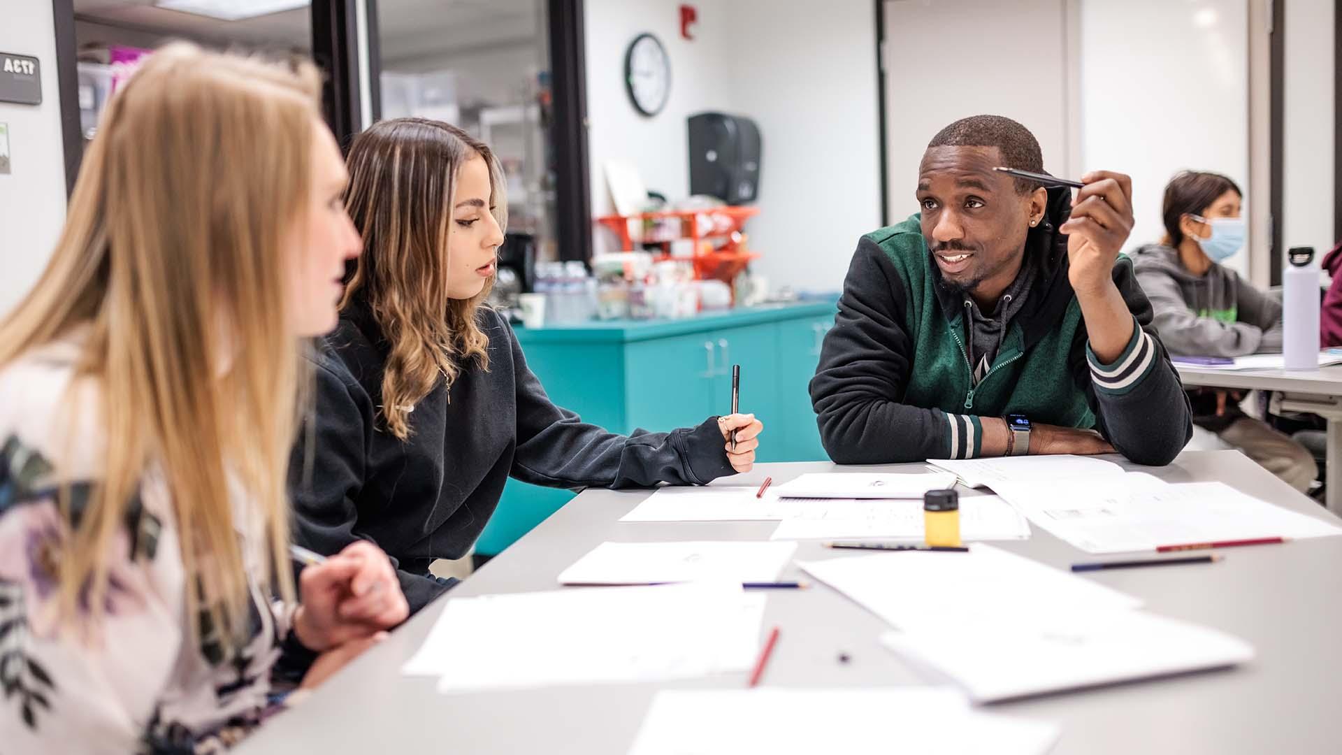 Students in a classroom discuss a group project.