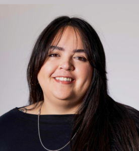 Woman, Shayla Bischoff, posing for a headshot. Black shirt, long black hair, smiling